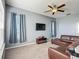 Upstairs loft area features a large sofa, TV and multiple windows with blue curtains at 2530 The Oaks Blvd, Kissimmee, FL 34746