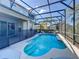 Beautiful in-ground pool is surrounded by a screened-in enclosure and landscaping at 2530 The Oaks Blvd, Kissimmee, FL 34746