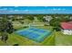 Aerial view of community tennis courts, framed by lush greenery and a glimpse of the surrounding neighborhood at 2530 The Oaks Blvd, Kissimmee, FL 34746