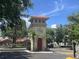 Clock tower at gated entrance with neatly manicured landscaping and clear blue sky at 2770 Club Cortile Cir # A, Kissimmee, FL 34746
