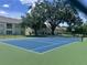 Community tennis court bordered by a fence, trees, and community buildings at 2770 Club Cortile Cir # A, Kissimmee, FL 34746