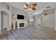 An open living room features wood floors, high ceilings with fans, fireplace and tv, and access to other rooms at 3196 Verbena Ct, Deltona, FL 32725