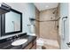 Bathroom features earth-toned tile, shower, and granite vanity with large mirror and black fixtures at 3201 Dallas Blvd, Orlando, FL 32833