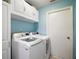 Bright laundry room with blue walls and white cabinets above the washer and dryer at 3271 Settlers Trl, St Cloud, FL 34772