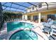 Beautiful screened-in pool and spa surrounded by seating and lush landscaping at 331 Bridgewater Dr, Davenport, FL 33897