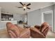 Living room featuring neutral walls, plush armchairs, ceiling fan, and an open layout to the kitchen at 3757 Conroy Rd # 2525, Orlando, FL 32839
