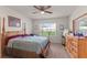 Bright bedroom showcasing a wooden four-poster bed, a ceiling fan, and view of the yard through a window at 3817 Heartleaf Ln, Mount Dora, FL 32757