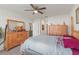 Cozy bedroom featuring a wooden dresser, ceiling fan, and a glimpse into the en-suite bathroom at 3817 Heartleaf Ln, Mount Dora, FL 32757