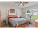 Relaxing bedroom with a four-poster bed, ceiling fan, and view of the outdoors through a window at 3817 Heartleaf Ln, Mount Dora, FL 32757