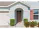 Close-up of entryway with well-maintained bushes, a brown door, and light peach-colored siding at 3817 Heartleaf Ln, Mount Dora, FL 32757