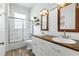 Bright bathroom featuring white vanity with double sinks, wood countertops, and modern sliding glass shower at 4825 Waterwitch Point Dr, Orlando, FL 32806
