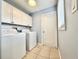 Bright laundry room features washer, dryer, upper cabinets, and a window for natural light at 5804 Plum Pudding Ct, Orlando, FL 32821