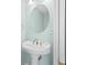Pedestal sink with brushed bronze fixtures and a round mirror in a light blue painted bathroom at 660 Celebration Ave # 250, Kissimmee, FL 34747
