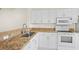 Well-lit kitchen with white appliances and cabinets complemented by granite countertops and tile floors at 660 Celebration Ave # 250, Kissimmee, FL 34747