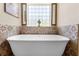 Luxurious freestanding bathtub with decorative tile surround and a window for natural light at 700 Old Geneva Rd, Geneva, FL 32732