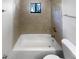 White bathtub, toilet, tiled wall and a peek out the window to the outdoors at 9744 Tattersall Ave, Orlando, FL 32817