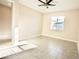 Bright, airy bedroom with neutral walls, ceiling fan, and a large window overlooking a treelined backyard at 1023 Sugarwood St, Davenport, FL 33837