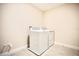Tiled laundry room with new, modern, white, front-loading washer and dryer machines at 1023 Sugarwood St, Davenport, FL 33837