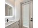 Bathroom with a white vanity, dark hardware, a lighted mirror, and a door to the outside at 10750 Sw 110Th St, Dunnellon, FL 34432