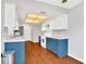 Bright kitchen featuring modern appliances, white upper cabinets, blue lower cabinets, and wood flooring at 110 Todd Dr, Casselberry, FL 32707