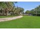 Expansive recreational area featuring a gravel driveway, lush green grass, and mature trees at 110 Todd Dr, Casselberry, FL 32707