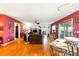 Open-concept living room featuring hardwood floors, red accent walls, a ceiling fan, and access to the outdoor patio at 130 Masterpiece Rd, Lake Wales, FL 33898
