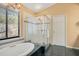 Bright bathroom featuring a soaking tub, glass enclosed shower, and large window at 1609 Glen Eagles Way, Orlando, FL 32804