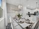 Well-lit dining area adjacent to kitchen, featuring a white table set for six, chandelier, and window at 17426 Saw Palmetto Ave, Clermont, FL 34714