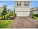 Beautiful two-story home with a two-car garage and a brick-paved driveway, complemented by lush landscaping at 17426 Saw Palmetto Ave, Clermont, FL 34714