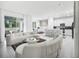 Bright, open-concept living space with modern white furniture, marble floors, and a stylish kitchen in the background at 17426 Saw Palmetto Ave, Clermont, FL 34714