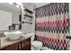 Bathroom featuring stylish vanity, modern vessel sink, decorative shower curtain, and black iron shelving at 2375 Belen Dr, Deltona, FL 32738