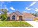 Charming single-story home with a brick facade, arched entryway, manicured lawn, and attached two car garage at 2444 Omaha Dr, Deltona, FL 32738
