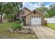 Charming tan home featuring a stone facade, large windows, mature landscaping, and an attached garage at 25438 Pine Valley Dr, Sorrento, FL 32776