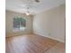 Bright room featuring wood-look flooring, ceiling fan, large window, and neutral paint at 26908 Honeymoon Ave, Leesburg, FL 34748