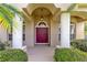 Elegant front entrance with a deep red door, arched entryway, and stately white pillars at 315 Belhaven Falls Dr, Ocoee, FL 34761
