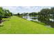 Serene backyard with lush lawn gently sloping to a pond with fountain and views of neighboring homes at 3419 Fernwood Dr, Kissimmee, FL 34741