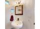 Charming powder room featuring a pedestal sink, decorative mirror, and unique glass block windows at 3728 Hunters Isle Dr, Orlando, FL 32837
