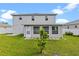 Well-maintained backyard featuring lush grass, a young tree, and a sunroom extension with a white back door at 404 Bar Ct, Kissimmee, FL 34759