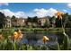 Scenic view of the community buildings with lush landscaping and a tranquil pond reflecting the clear blue sky at 506 Mirasol Cir # 202, Celebration, FL 34747