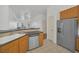 Well-lit kitchen featuring stainless steel dishwasher and refrigerator, combined with tiled floor and wooden cabinets at 506 Mirasol Cir # 202, Celebration, FL 34747