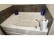 Stylish bathtub featuring modern fixtures, a smooth white finish, and neutral-toned stone tiling around the rim at 5169 Dove Tree, Orlando, FL 32811