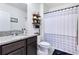 Bathroom featuring granite countertop, dark cabinets, and a shower with striped shower curtain at 633 Greymount St, Davenport, FL 33837