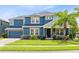 Charming two-story home boasts a manicured lawn, blue exterior, and inviting front porch at 11850 Sheltering Pine Dr, Orlando, FL 32836