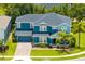 Stunning blue two-story home featuring lush landscaping, a well-manicured lawn, and a charming front porch at 11850 Sheltering Pine Dr, Orlando, FL 32836