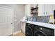 Modern laundry room with sink, marble counter, black and white tile backsplash, and front loading machines at 11850 Sheltering Pine Dr, Orlando, FL 32836