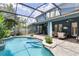 A screened-in pool area showcases a step-in pool with brick pavers and lush landscaping at 11850 Sheltering Pine Dr, Orlando, FL 32836