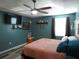 Relaxing bedroom features wood look floors, ceiling fan, mounted TV, and decor shelves for a personal touch at 1420 Center St, Ocoee, FL 34761