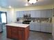 Bright kitchen showcasing gray cabinets, tile backsplash, stainless steel appliances, and a central island with marble countertop at 1420 Center St, Ocoee, FL 34761
