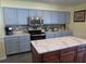 Spacious kitchen featuring stainless steel appliances, grey cabinets, and a large island with a marble countertop at 1420 Center St, Ocoee, FL 34761