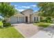 Inviting single-story home with a brick driveway, well-kept lawn and two-car garage at 15424 Sweet Orange Ave, Winter Garden, FL 34787